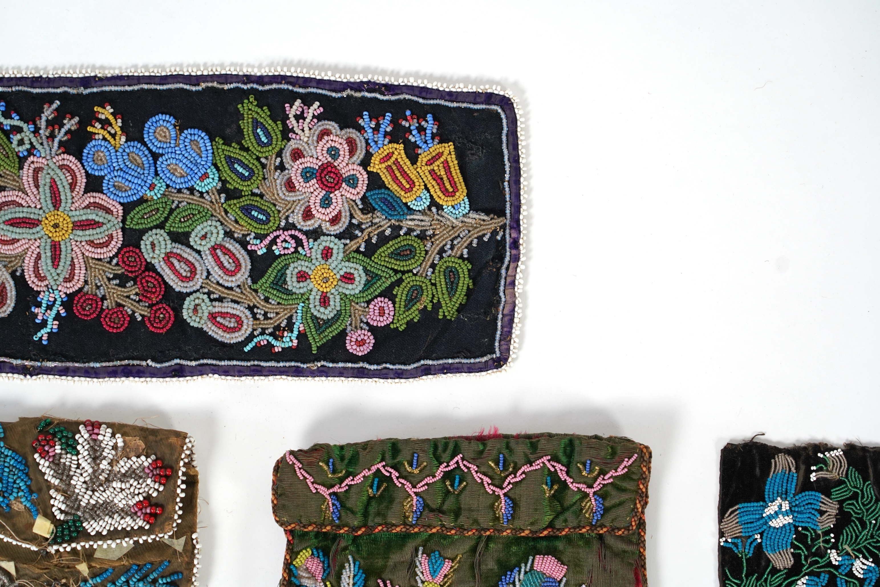 A 19th century black felt multi coloured beadwork panel, possibly North American Indian and a similar purse, a Regency fine bead worked bible bag, a similar worked belt and small panel, a red bead work purse and a small